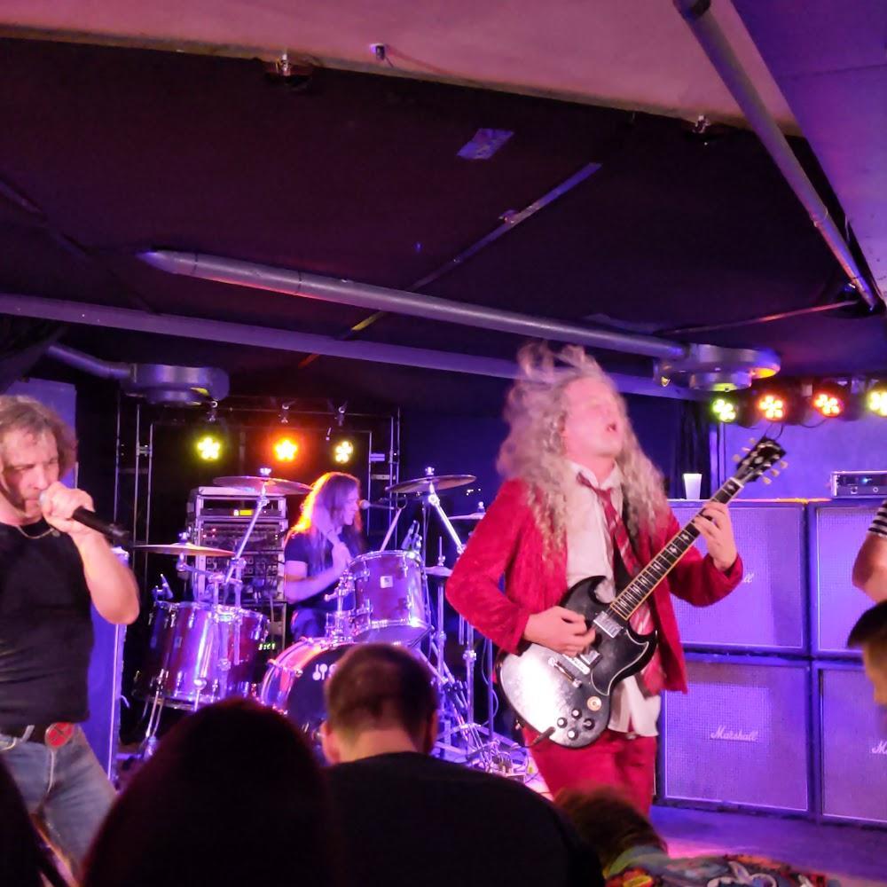 A rock band performing on stage with a drummer and a guitarist.